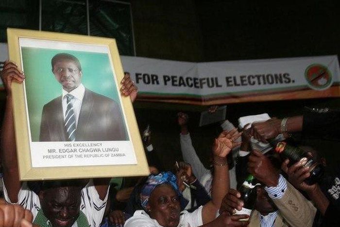 Patriotic Front General Secretary Davies Chama (L) celebrates while holding a portrait of President Edgar Chagwa Lungu after Lungu narrowly won re-election on Monday in the capital, Lusaka, Zambia, August 15, 2016.