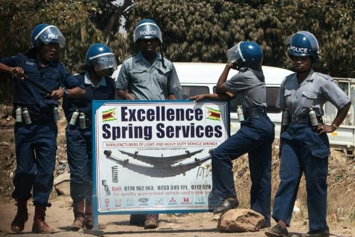 Zimbabwean police in anti-riot gear stand by a road sign as they patrol the streets as opposition protest for political reforms fails to kick off