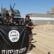 Iraqi security forces stand with an Islamic State flag which they pulled down in the town of Hit in Anbar province, April 2, 2016.