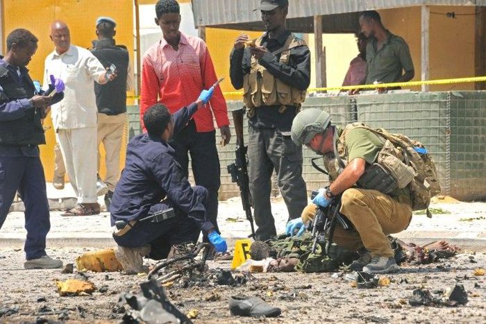 A foreign security officer checks a body at the scene of a suicide attack in Mogadishu, on July 31, 2016 