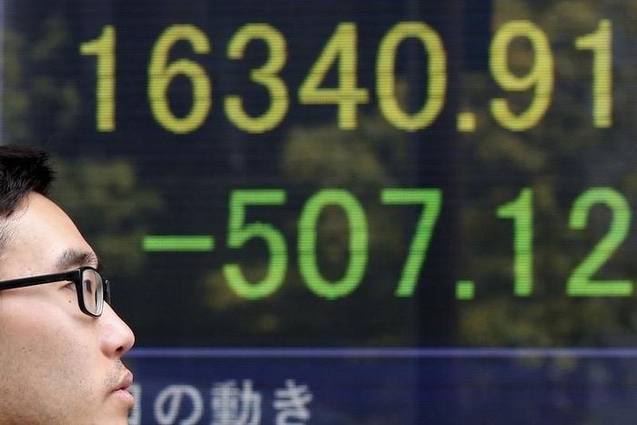 A man walks in front of an electronic board showing Japan's Nikkei average outside a brokerage in Tokyo, Japan, April 18, 2016.