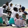 Migrants sit after they disembarked from Italian Navy ship Sirio in the Sicilian harbour of Augusta, Italy, August 21, 2016.