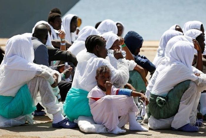 Migrants sit after they disembarked from Italian Navy ship Sirio in the Sicilian harbour of Augusta, Italy, August 21, 2016.