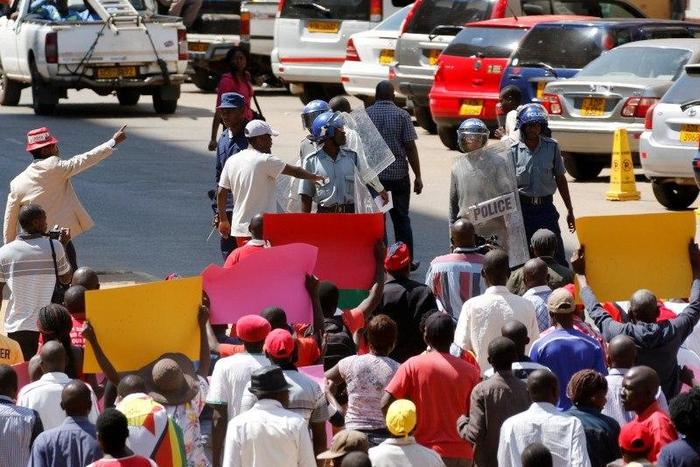 Locals hold placards during a protest by opposition youths who were demonstrating against alleged brutality by security agents in the capital Harare, Zimbabwe August 24, 2016.