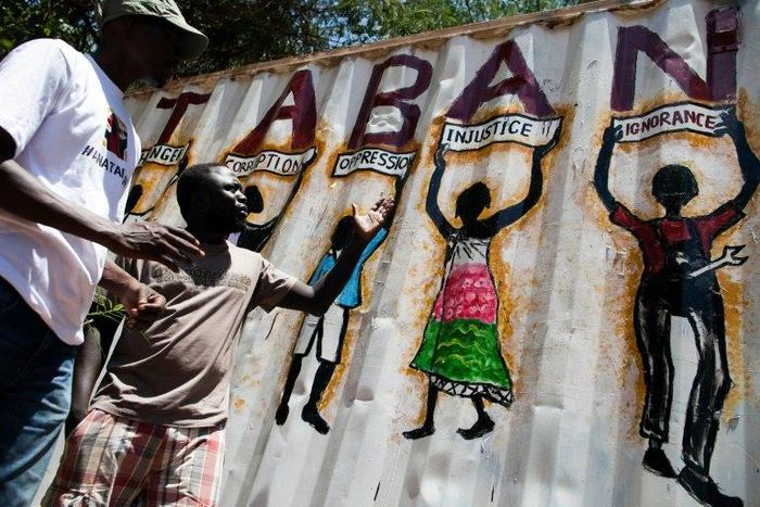 Painter Thomas Dai (L) and musician James Aka, both members of the new activist movement #AnaTaban, talk in front of Thomas' latest graffiti in a street in Juba, South Sudan