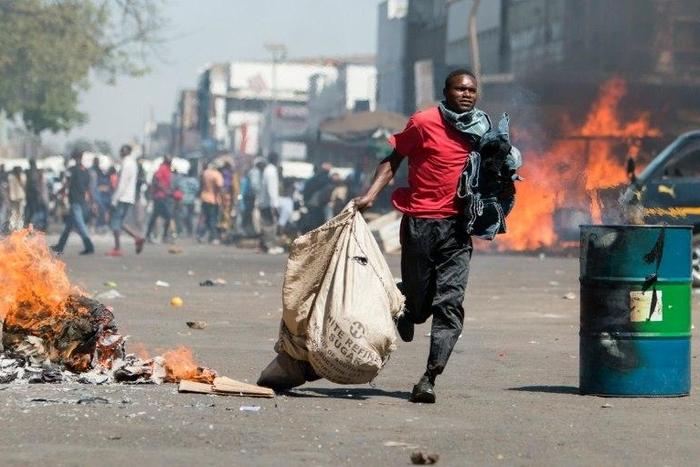 A street vendor flees with his goods as Zimbabwe opposition supporters clash with police in Harare on August 26, 2016