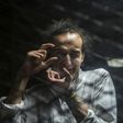 Egyptian photographer Mahmoud Abdel Shakour, known as Shawkan, gestures from inside a soundproof glass dock, during his trial in Cairo on August 9, 2016 