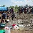 This handout photo provided by the United Nations Mission in the Republic of South Sudan (UNMISS) and released on July 16, 2016 shows women doing laundry as people collect water at the UN compound in the Tomping area in Juba 