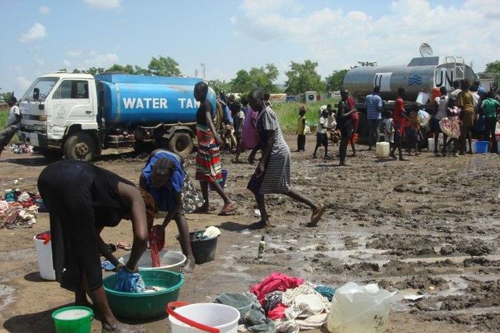 This handout photo provided by the United Nations Mission in the Republic of South Sudan (UNMISS) and released on July 16, 2016 shows women doing laundry as people collect water at the UN compound in the Tomping area in Juba 