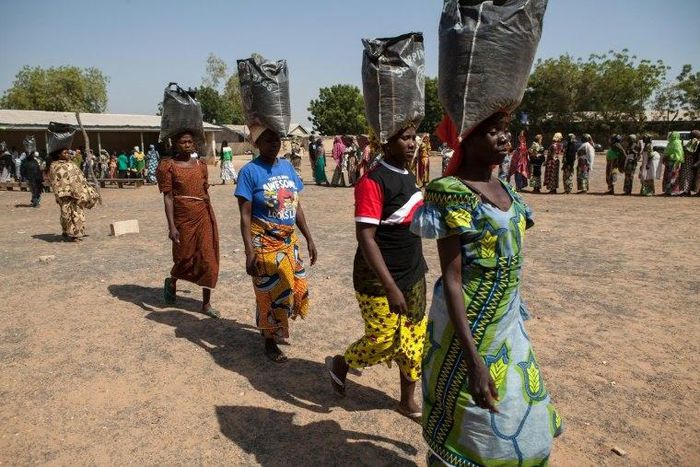 This photo taken on December 4, 2014 shows displaced women carrying sacks of food aid received during a distribution at the Cathedral of Yola, state capital of Adamawa 