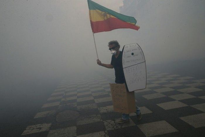 A man holds Ethiopia's former flag as he tries to prevent clashes between protesters and police during a demonstration 