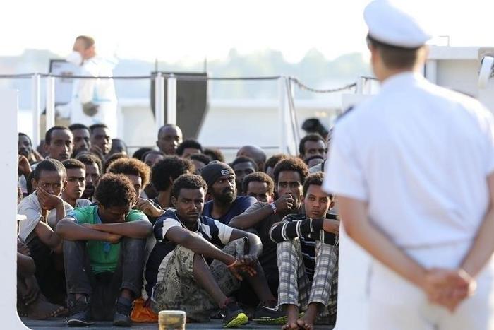 Migrants wait to disembark from a Coast Guard ship in the Sicilian harbour of Messina, Italy August 29, 2015.