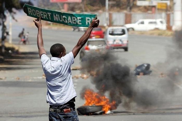 A man carries a street sign as opposition party supporters clash with police in Harare, Zimbabwe, August 26,2016. REUTERS/Philimon Bulawayo