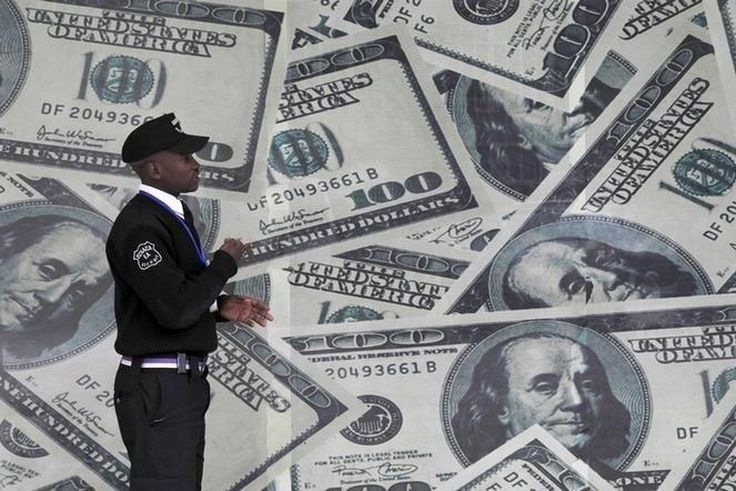 A security guard walks past a montage of U.S. dollar bills outside a currency exchange bureau in Kenya's capital Nairobi, July 23, 2015.    REUTERS/Thomas Mukoya/File Photo
