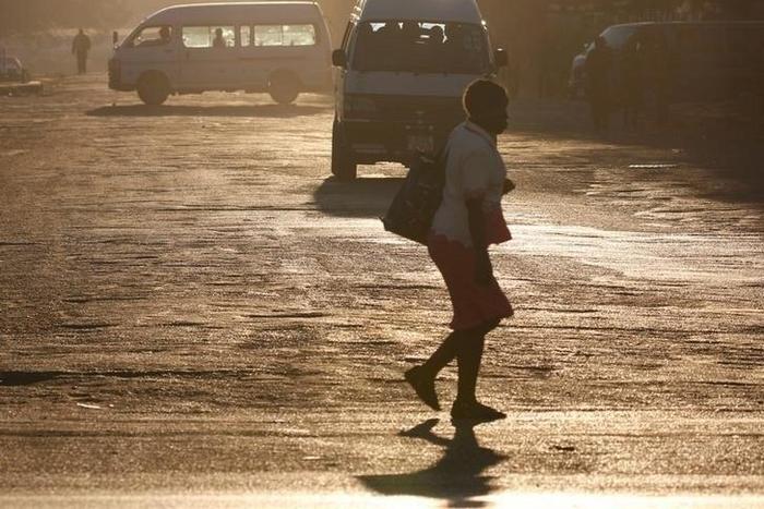 A woman crosses the street in front of minibus taxis in Harare, Zimbabwe, August 31, 2016.   REUTERS/Philimon Bulawayo