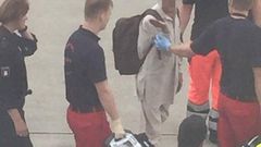 The passenger being escorted by the medical crew from the airport