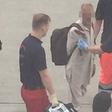 The passenger being escorted by the medical crew from the airport