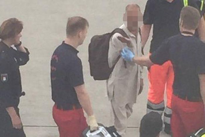 The passenger being escorted by the medical crew from the airport