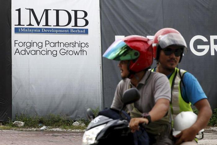 Motorcyclists pass a 1Malaysia Development Berhad (1MDB) billboard at the Tun Razak Exchange development in Kuala Lumpur, Malaysia, February 3, 2016. REUTERS/Olivia Harris/File Photo