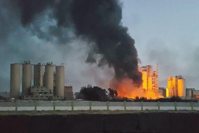 A fire next to the Libyan cement factory is seen during clashes between military forces loyal to Libya's eastern government, who are backed by the locals, and the Shura Council of Libyan Revolutionaries, an alliance of former anti-Gaddafi rebels, who h...