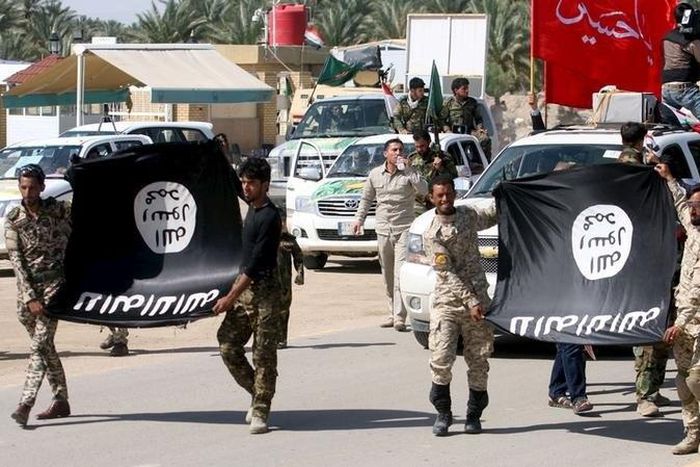 Shi'ite paramilitary fighters hold an Islamist State flag which they pulled down during victory celebrations after returning from Tikrit in Kerbala, southwest of Baghdad April 4, 2015.    REUTERS/Mushtaq Muhammed
