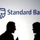 Businessmen chat in front of a Standard Bank logo in Sandton outside Johannesburg in a file photo.Sibeko