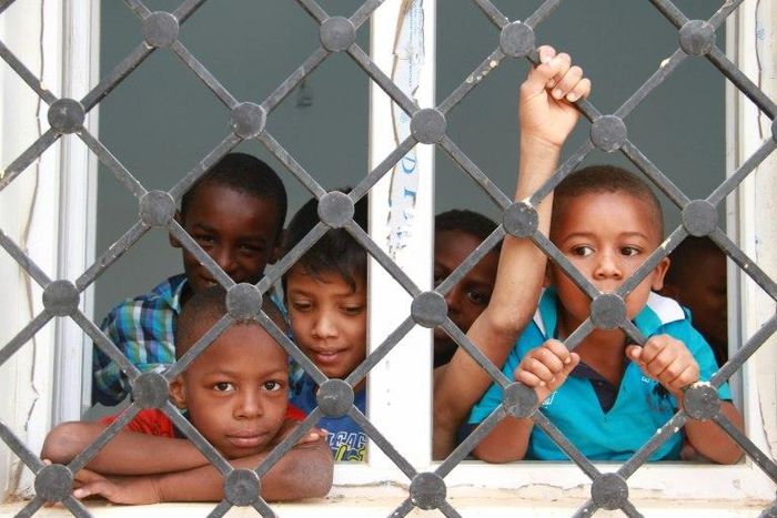 Displaced Libyan children who fled the eastern Libyan cities of Abu Grein and Sirte look out of window at a school where they are taking shelter in Bani Walid, in May 2016