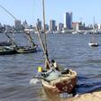A fisherman cleans his boat beneath Maputo's skyline, Mozambique, August 15, 2015.
