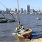 A fisherman cleans his boat beneath Maputo's skyline, Mozambique, August 15, 2015.