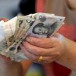 A vendor holds Chinese Yuan notes at a market in Beijing, August 12, 2015. REUTERS/Jason Lee