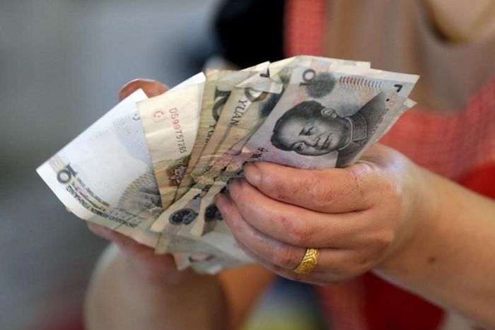 A vendor holds Chinese Yuan notes at a market in Beijing, August 12, 2015. REUTERS/Jason Lee