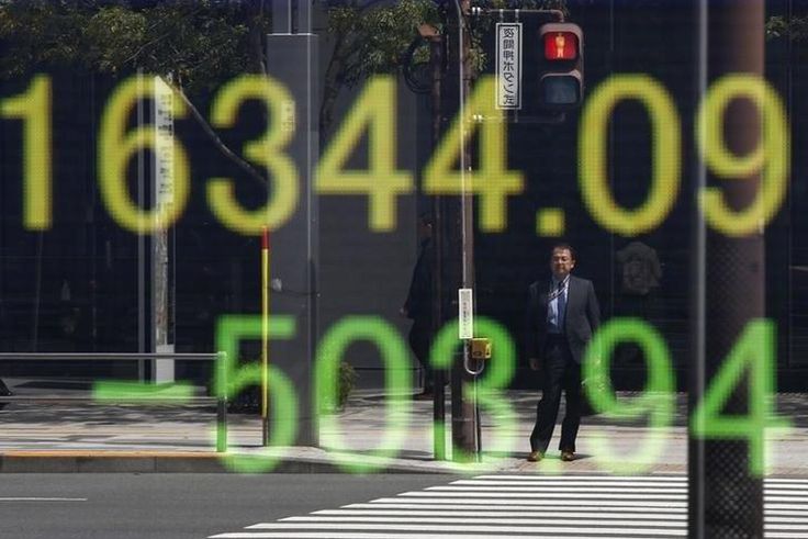 A businessman is reflected in an electronic board displaying Japan's Nikkei share average outside a brokerage in Tokyo, Japan, April 18, 2016.