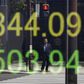 A businessman is reflected in an electronic board displaying Japan's Nikkei share average outside a brokerage in Tokyo, Japan, April 18, 2016.