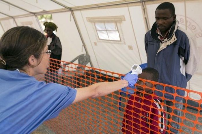 A health worker checks the temperature of a boy at the entrance to a Red Cross facility in the town of Koidu, Kono district in Eastern Sierra Leone December 19, 2014.