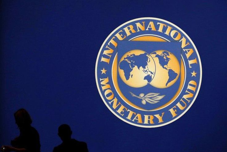 Visitors are silhouetted against the logo of the International Monetary Fund at the main venue for the IMF and World Bank annual meeting in Tokyo October 10, 2012.