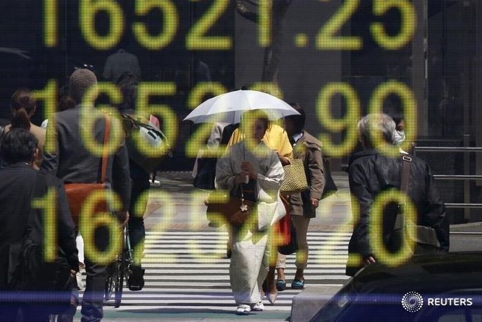 A woman clad in a kimono is reflected in an electronic board displaying Japan's Nikkei share average outside a brokerage in Tokyo, Japan, April 18, 2016.
