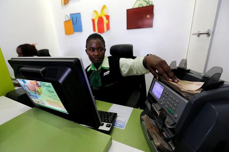An employee uses a money counting machine as she serves a customer inside a mobile phone care centre operated by Kenyan's telecom operator Safaricom; in the central business district of Kenya's capital Nairobi, May 11, 2016.