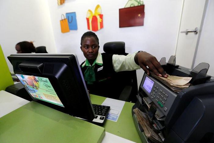 An employee uses a money counting machine as she serves a customer inside a mobile phone care centre operated by Kenyan's telecom operator Safaricom; in the central business district of Kenya's capital Nairobi, May 11, 2016.