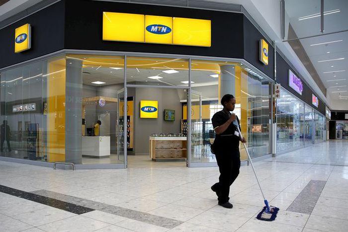 A worker sweeps past an outlet of South Africa's MTN Group in Johannesburg, February 23, 2016.  REUTERS/Siphiwe Sibeko