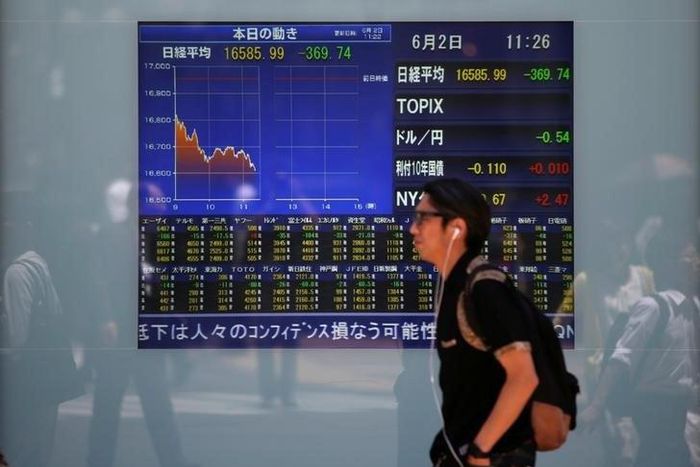 A man walks in front of a screen showing today's movements of Nikkei share average outside a brokerage in Tokyo, Japan, June 2, 2016.