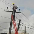 A man standing against a ladder on an electricity pole
