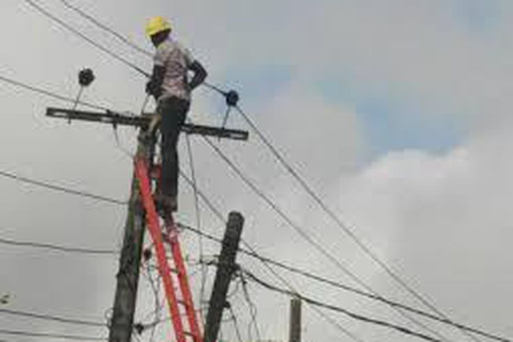 A man standing against a ladder on an electricity pole