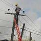 A man standing against a ladder on an electricity pole