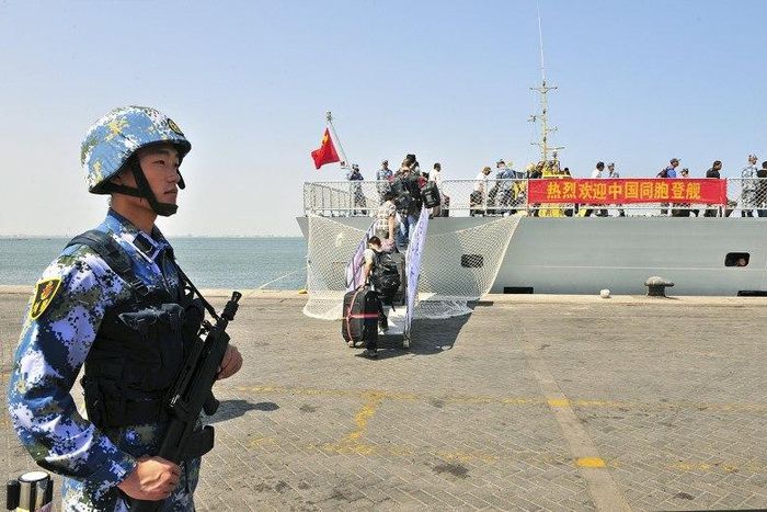 A navy soldier (L) of People's Liberation Army (PLA) stands guard as Chinese citizens board the naval ship "Linyi" at a port in Aden, in this March 29, 2015 file photo. REUTERS/Stringer/Files