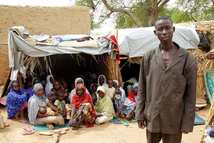 Aba Ali, a Nigerian refugee who fled from his village in northeastern Nigeria into Niger following Boko Haram attacks, stands next to his relatives at the home of Adamu Moumouni, his Nigerien host who took them in, in Diffa in southeastern Niger June 2...