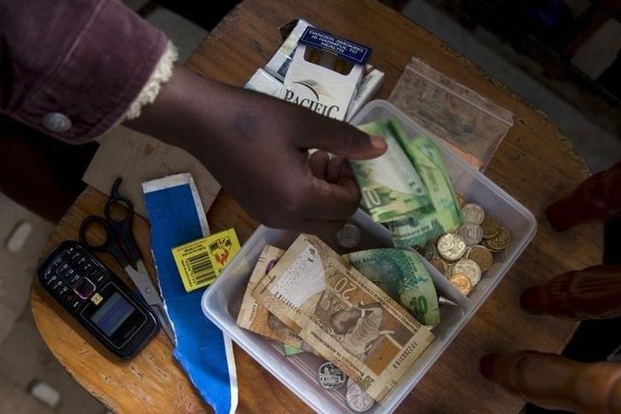 A shopkeeper puts money in her cash box at her shop in Hillcrest west of Durban, South Africa, January 11, 2016.