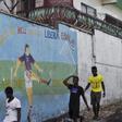 Men walk by a mural that reads "Get the hell of Liberia, Ebola! And don't come back" in Monrovia, Liberia, April 1, 2016. REUTERS/James Giahyue
