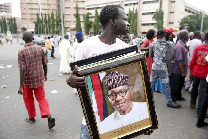 A man holds a framed portrait of Nigeria's President Muhammadu Buhari outside the venue of Buhari's inauguration in Abuja May 29, 2015. REUTERS/Akintunde Akinleye
