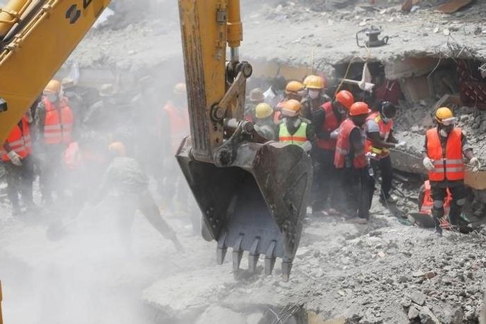 Rescuers use an excavator as they attempt to evacuate a woman from the rubble of a six-storey building that collapsed last Friday after days of heavy rain, in Nairobi, Kenya May 5, 2016.
