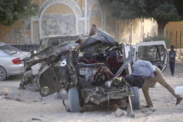 A Somali police officer looks inside the wreckage of a car destroyed when Islamist militants opened fire on government officials in a car and then a car bomb exploded, according to police and a spokesman for Mogadishu's mayor, in Yaqshiid district of S...
